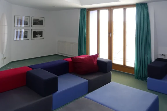 Raum mit bunten Sitzgelegenheiten und Fenster.